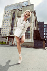 mischievous ballerina walks down the street on a summer day against the background of an old...