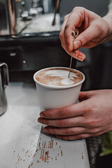 Artful barista drizzles caramel on a fresh cappuccino, showcasing intricate skill and attention to detail in crafting specialty coffee