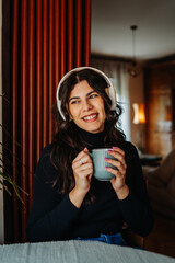 One young caucasian woman is listening to music on her wireless headphones in the morning before going to work	
