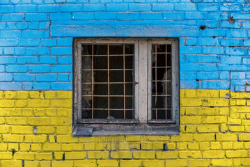 pattern explosion damaged blue yellow house wall with window in Ukraine