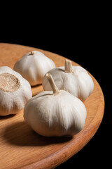 Garlic on a wooden kitchen board on a black background. Organic garlic - 792634378