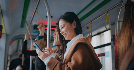 People commuting in public transport during daytime. Camera focus on Asian girl standing in middle...