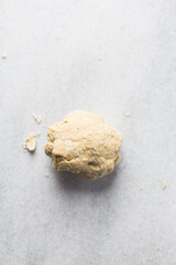 Overhead view of egg noodles dough being mixed on a marble countertop, process of making fresh egg noodles