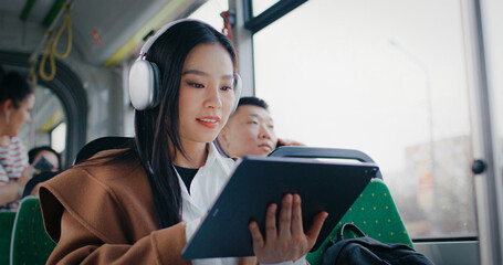 Young Chinese girl with long black hair using tablet with big screen. Navigating in device with one...