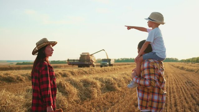 Family walk man son mom on nature at sunset. Father holding boy on shoulders walking on field with haystacks. Child with flying arms playing with dad. People enjoying nature, farmland childhood.