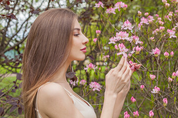 Brunette fashion model with long brown hair and natural makeup against floral background outdoor