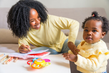 Adorable child and african mother drawing at home