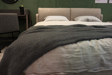 A dark brown plaid lies on a double bed with white linens