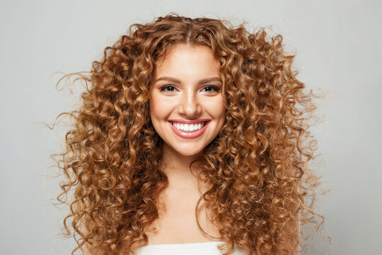 Laughing young woman redhead with long healthy hair and fresh silky skin posing on white background. Fashion beauty studio portrait