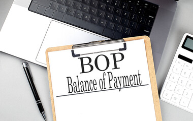 BOP- BALANCE OF PAYMENT word on clipboard on laptop with calculator and pen - obrazy, fototapety, plakaty