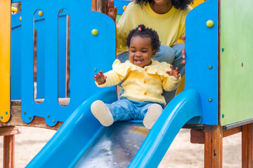 Baby girl sliding in a blue slide in a park
