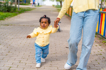 African mother and baby girl walking holding hands outdoors