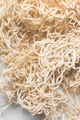 Overhead view of dried homemade egg noodles on a marble countertop, top view of air-dried egg noodles