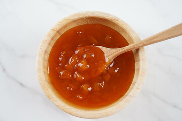 Peach jam in a wooden bowl.  Canned fruit jam with ingredients