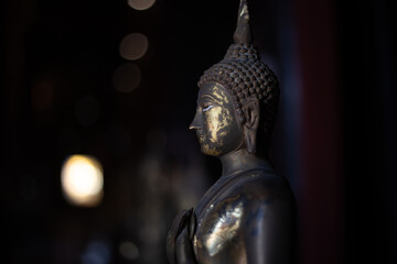 selective focus old brass Buddha statue in the dark In a temple in Thailand There is space for text.