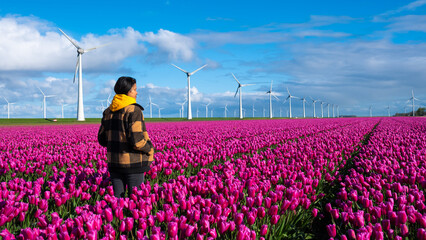 A man stands gracefully in a sea of purple tulips, surrounded by the vibrant colors of spring in...