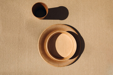 A set of paper utensils, cups and plates, on a brown background. Eco friendly, zero waste concept. Top view
