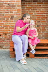 Deaf child with cochlear implant for hearing audio and aid for impairment having fun and laughs with mother outdoor in summer. Sound fitting device to help with communication listening and interaction - 792663377