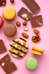 Pastel macarons, almond chocolate, peanut butter cookies and various nuts on bright pink background. Top view.