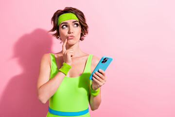 Fototapeta premium Photo of doubtful unsure woman dressed neon sporty bodysuit finger lips texting modern device empty space isolated pink color background