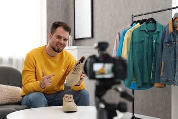 Smiling fashion blogger showing shoes while recording video at home