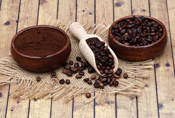 Kaffeebohnen und Kaffeepulver in Holzbehältern.