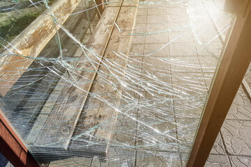 Vandalised Broken bus stop in the city. Dangerous, crashed tempered glass pieces on ground