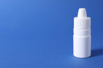 Bottle of medical drops on blue background, space for text