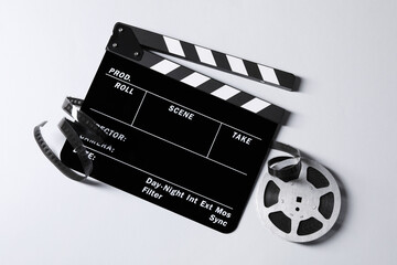 Clapperboard and film reel on grey background, flat lay