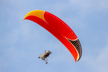 Paraglider With Engine Is Flying In The Blue Sky. Paragliding Is The Recreational Adventure Sport.