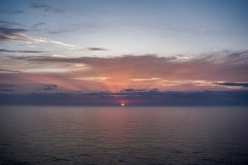 Colorful ocean beach sunrise with deep blue sky and sun rays