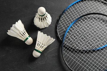 Feather badminton shuttlecocks and rackets on grey textured table, flat lay