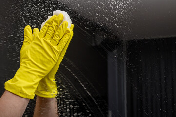 Mycie lustra w żółtych gumowych rękawicach ochronnych, porządki w domu 