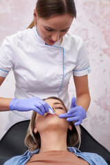Beautician cleaning patient's face before the beauty procedure