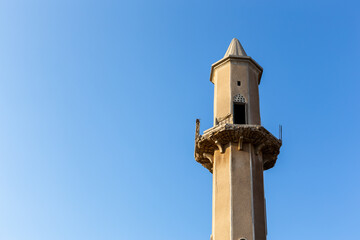 Old destroyed sandstone minaret of a mosque against crystal blue sky background in Al Jazirah Al...