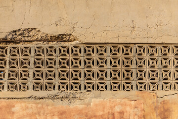 Old stone wall with openwork arabic ornaments in Al Jazirah Al Hamra haunted town in Ras Al...