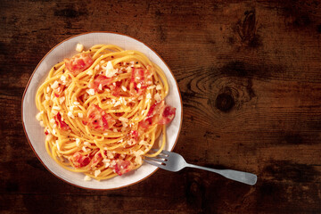 Carbonara pasta dish, traditional Italian spaghetti with pancetta and cheese, overhead flat lay shot with a fork and copy space, on a rustic background