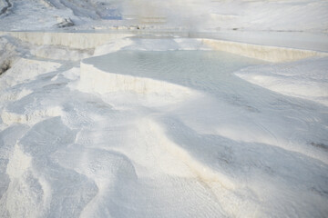 Close view of Pamukkale's cascading thermal water basins with textured white surfaces in Denizli,...