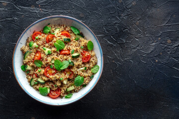Quinoa tabbouleh salad in a bowl, a healthy dinner with tomatoes and mint, overhead shot with copy space