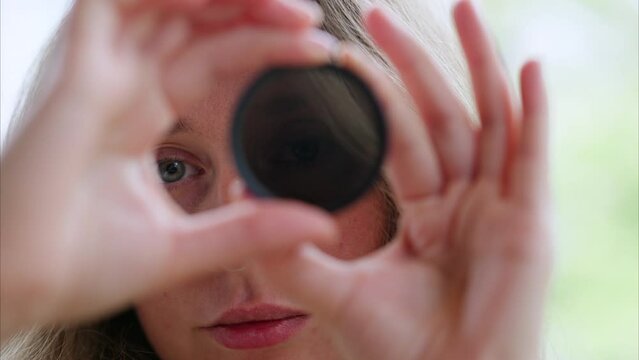 Woman looking through camera lens neutral density nd filter while rotating it