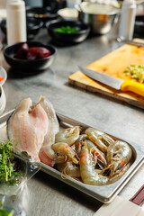 Restaurant's prep table displays raw fish, prawns, and perch fillets. Organized with cutting board and knife for immediate cooking