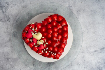 Strawberry cake in the shape of a heart, top view on a gray background.