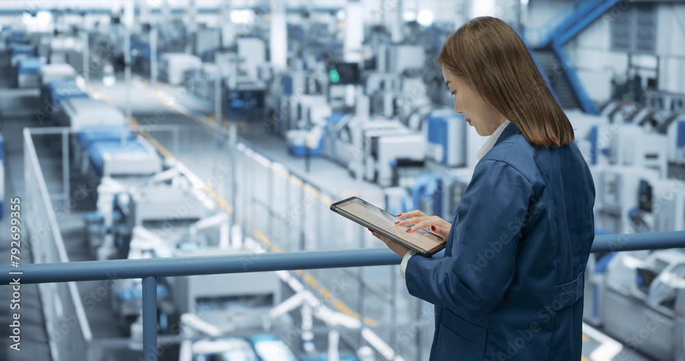 Aufkleber Experienced Female Engineer Standing on a Platform, Using Tablet Computer and Overlooking Production at a Modern Automated Electronics Manufacture with AI Support. Factory Manager at Work
