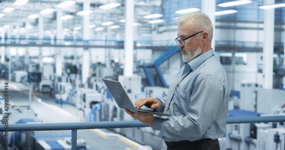 Poster Electronics Manufacturing Technician Working on a Laptop Computer at a Factory Space. Specialist Developing, Maintaining, Fine-Tuning Programs for Machine Production and Assembly