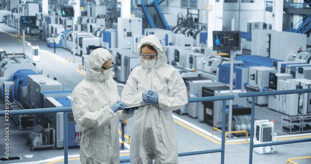 Aufkleber female workers wearing full-body polypropylene coveralls at a manufacturing plant. specialists using