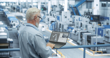 Portrait of a Handsome Middle Aged Engineer with Glasses Using Laptop Computer and Looking Around a Factory Facility with Equipment Producing Modern Electronic Components for Different Industries - 792699908