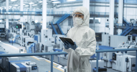 Industrial Scientist Wearing Disposable Protective Suit, Mask and Goggles at a Production Plant....