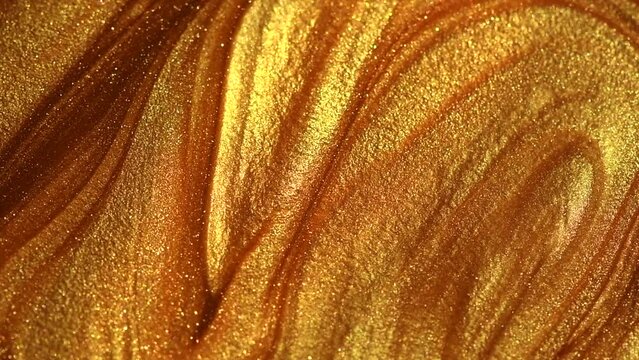 Beautiful abstract golden liquid paint background, beauty gold backdrop texture. Metallic gold paint, art design. Yellow shimmering surface close-up. Golden bright glitter texture, macro shot. 