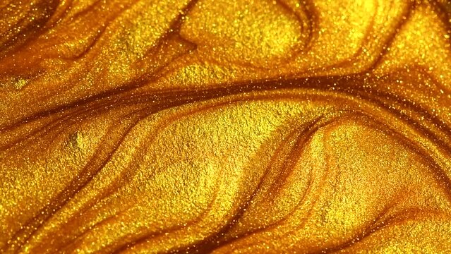 Beautiful abstract golden liquid paint background, beauty gold backdrop texture. Metallic gold paint, art design. Yellow shimmering surface close-up. Golden bright glitter texture, macro shot