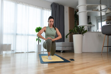 Athletic business woman in sportswear doing fitness yoga stretching exercises at home in the living room. Sport and recreation concept, healthy life and balance before work.